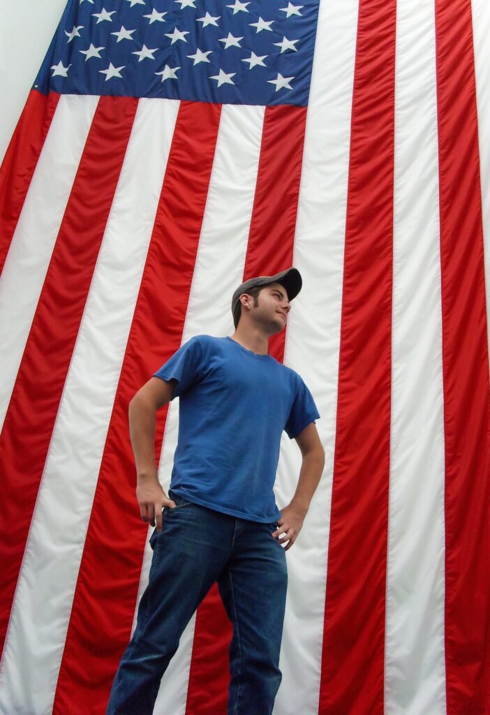 Man standing in front of United States red white and blue flag as a patriotic man