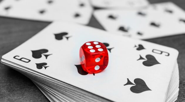 Red dice lie on a deck of playing cards in a casino. Casino gambling with dice and cards